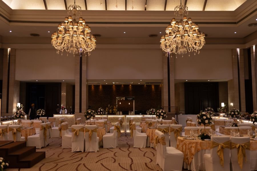 Ballroom banquet setup with chandeliers and gold chair styling