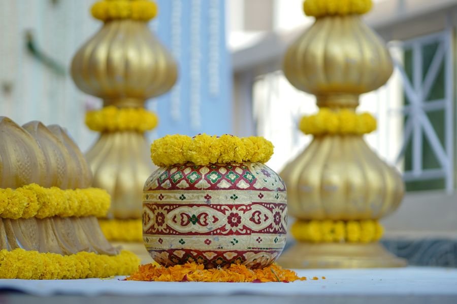 Marigold-draped kalash and brass urns for a ceremony setup