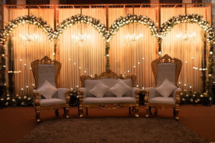 Gilded wedding stage with floral arches and chandeliers